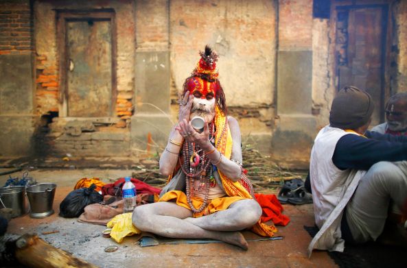 Hindu holy man, or sadhu, looks into the mirror as he applies ashes on his face at the premises of Pashupatinath Temple in Kathmandu February 16, 2015. Hindu holy men from Nepal and India come to this temple to take part in the Maha Shivaratri festival. Celebrated by Hindu devotees all over the world, Shivaratri is dedicated to Lord Shiva, and holy men mark the occasion by praying, smoking marijuana or smearing their bodies with ashes. REUTERS/Navesh Chitrakar (NEPAL - Tags: RELIGION SOCIETY TPX IMAGES OF THE DAY)