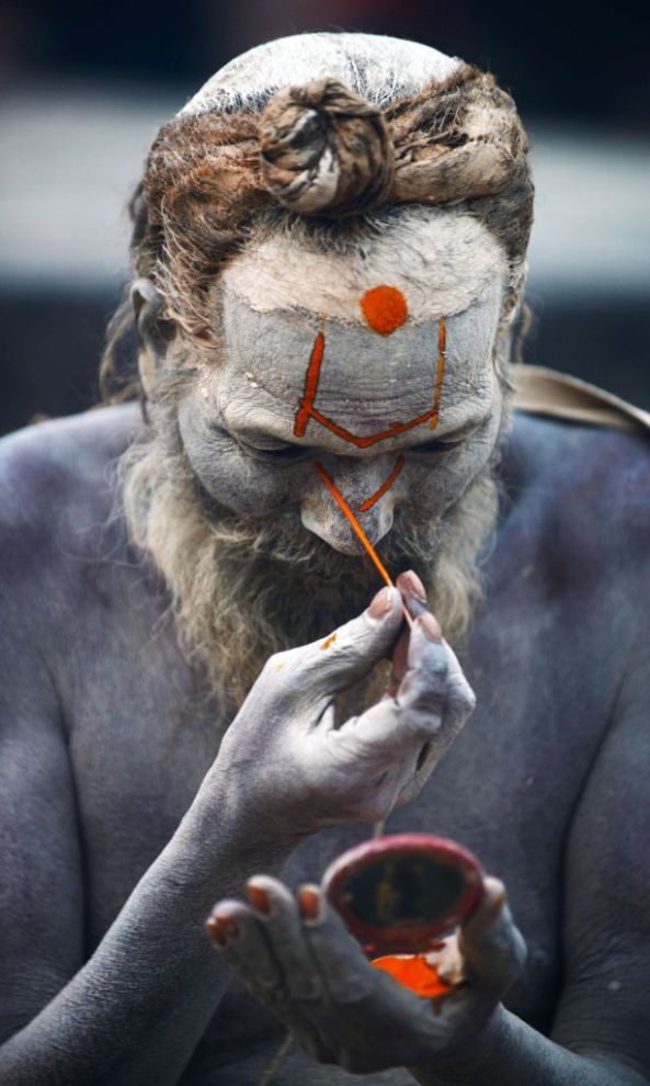 A Nepalese Hindu Sadhu (holy man) paints coloured paste onto his face during the Maha Shivaratri festival in Kathmandu on February 17, 2015. Hindus mark the Maha Shivratri festival by offering prayers and fasting. Hundreds of sadhus have arrived in Pashupatinath to take part in the event. AFP PHOTO / PRAKASH MATHEMA