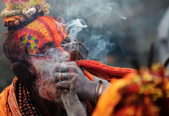 A Nepalese Hindu Sadhu (holy man) smokes marijuana from a clay pipe as a holy offering for Lord Shiva, the Hindu god of creation and destruction, during the Maha Shivaratri festival in Kathmandu on February 17, 2015. Hindus mark the Maha Shivratri festival by offering prayers and fasting. Hundreds of sadhus have arrived in Pashupatinath to take part in the event. AFP PHOTO / PRAKASH MATHEMA